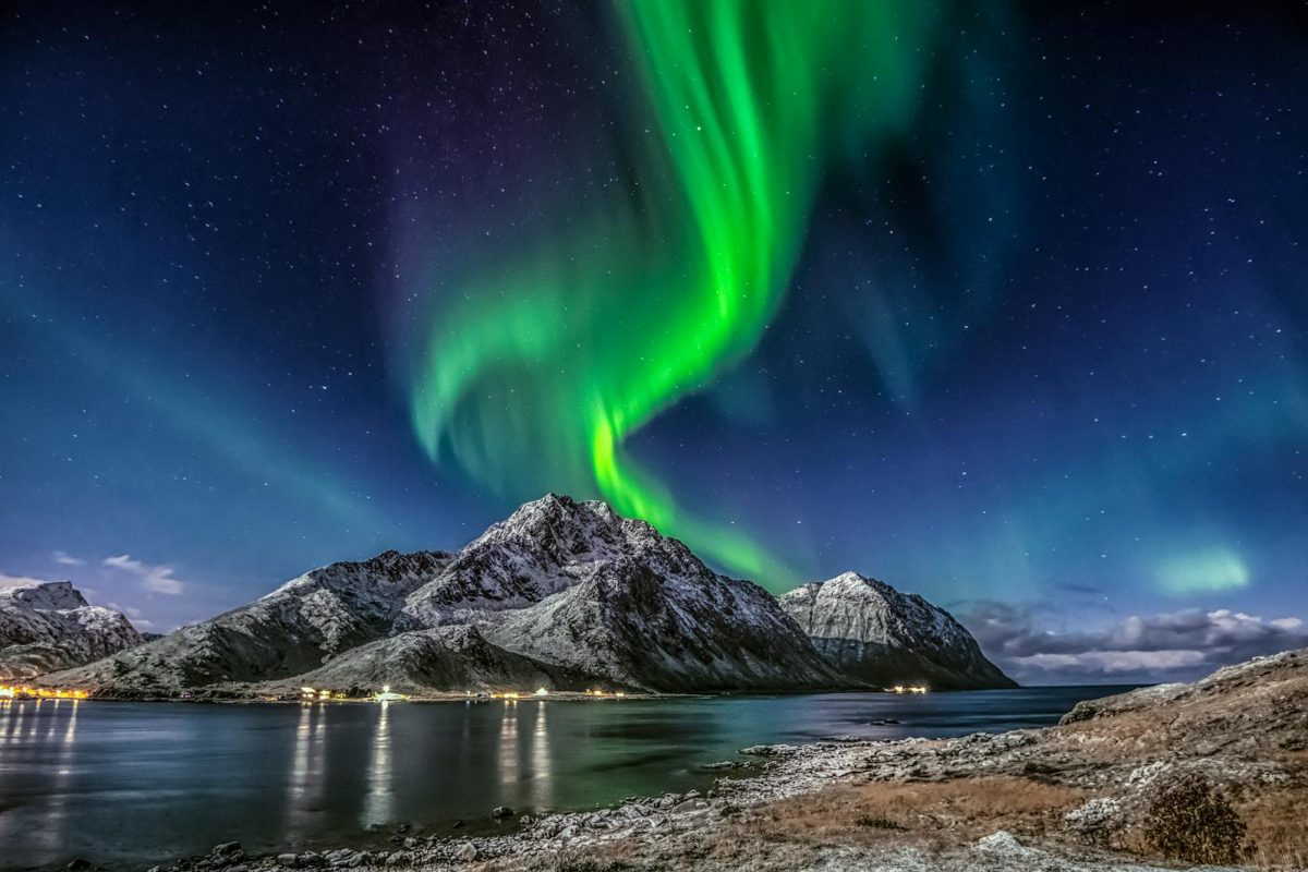 Stunning northern lights over snow-covered mountains in Nordland, Norway.
