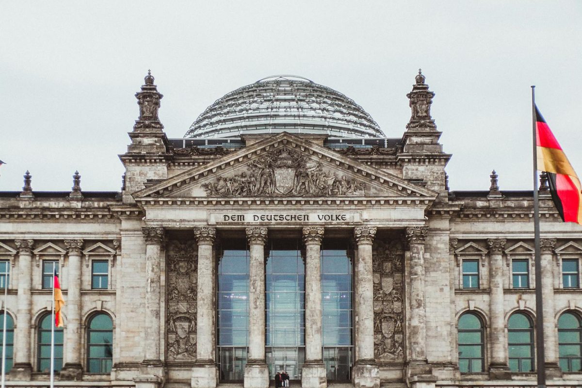 Front view of the historic Reichstag Building in Berlin, Germany, featuring prominent German flags.