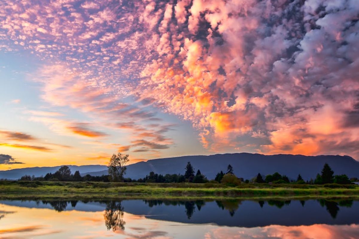Captivating sunset with vibrant clouds and serene reflections over Pitt Meadows, BC.