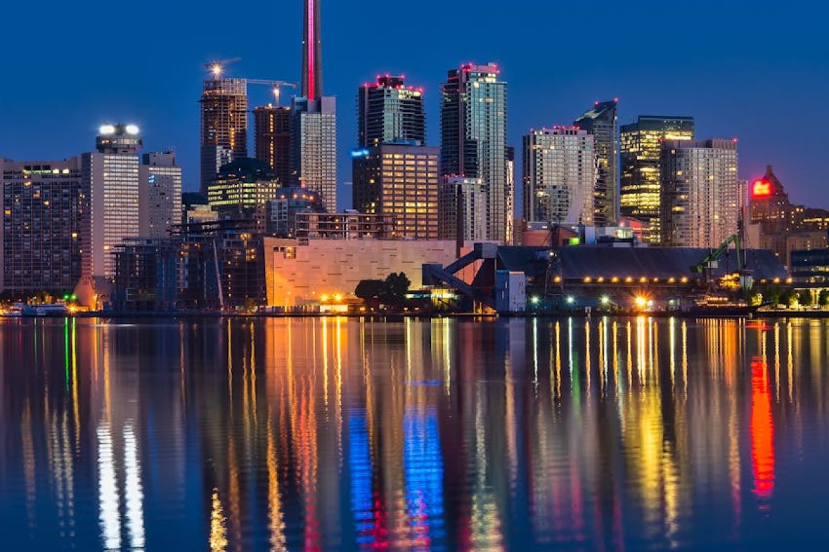 Beautiful nighttime view of Toronto skyline and CN Tower reflecting on calm water.