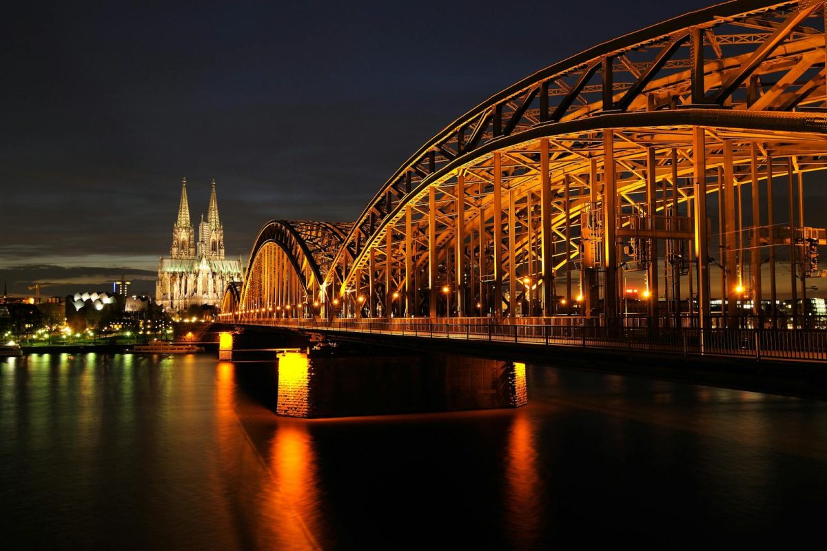 Captivating night shot of Cologne Cathedral and Hohenzollern Bridge reflected on the Rhine River.