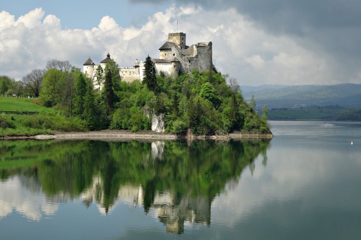Niedzica Castle reflecting on the serene lake surrounded by lush greenery.