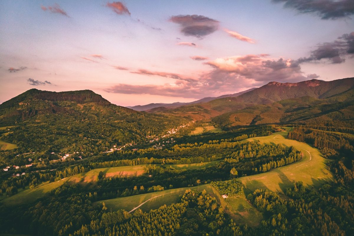 green trees and mountains under cloudy sky during daytime