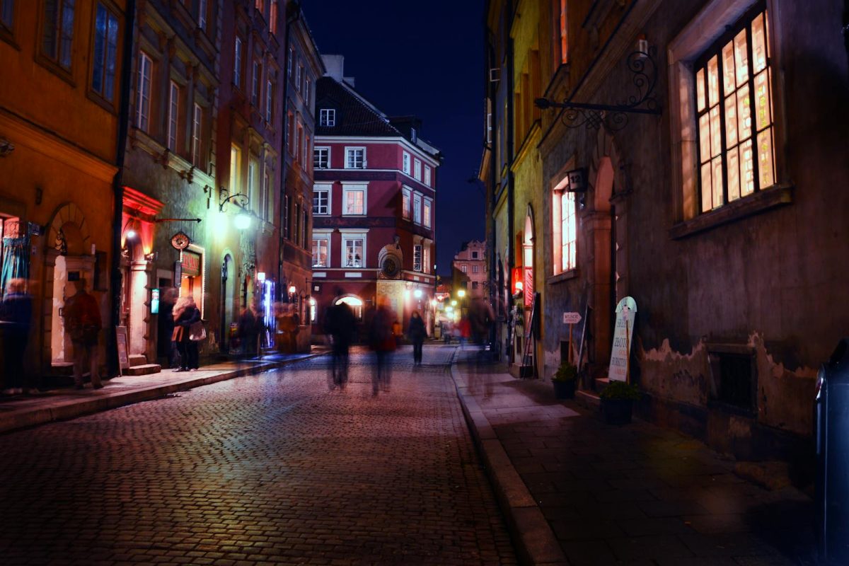 Charming night scene in a historic European city with blurred figures strolling under warm streetlights.