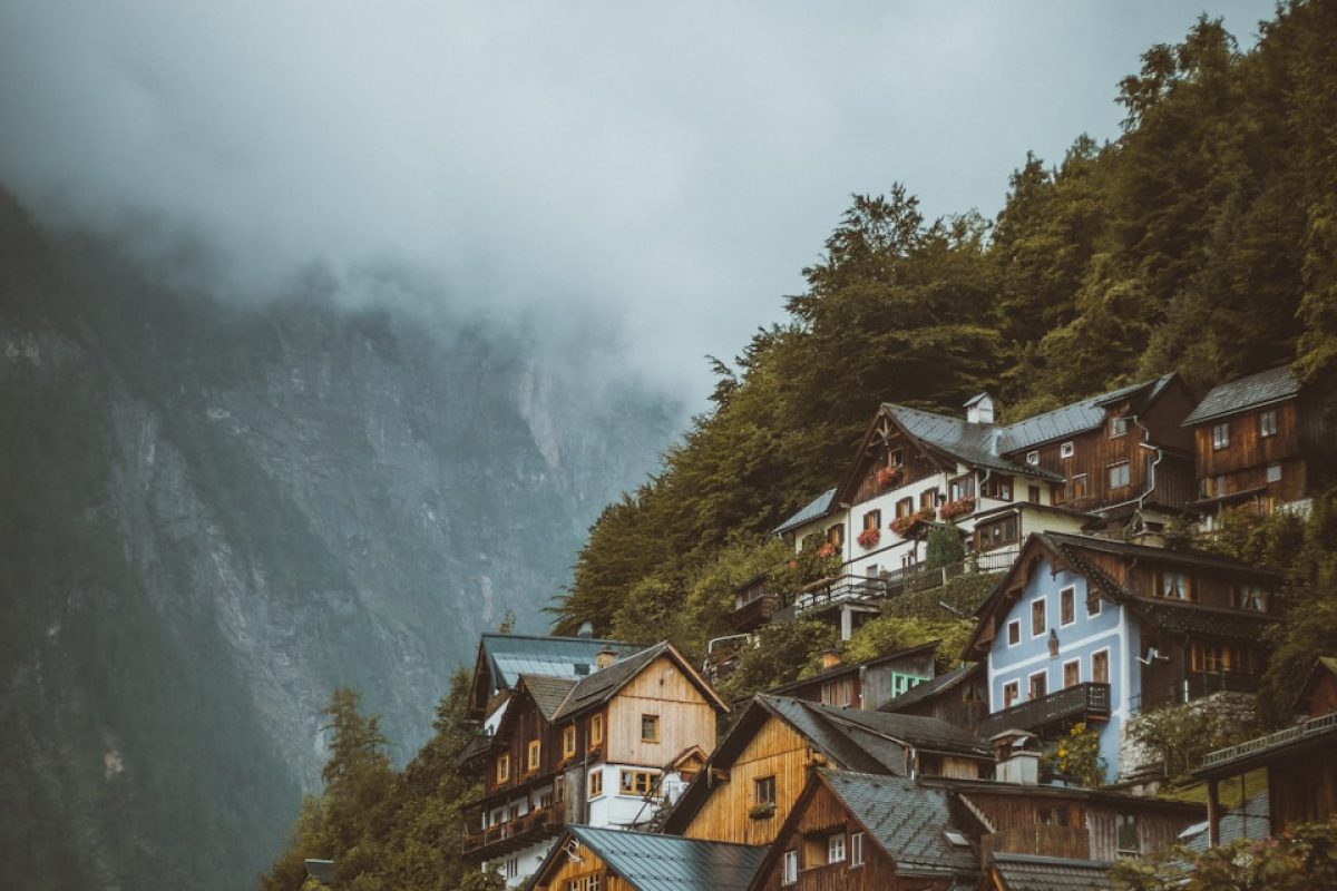 brown and white concrete houses near green trees and mountain during daytime