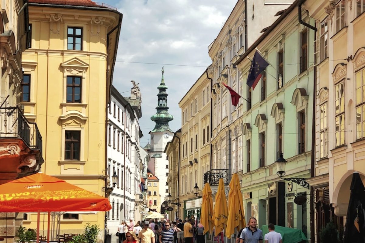 a group of people walking down a street next to tall buildings