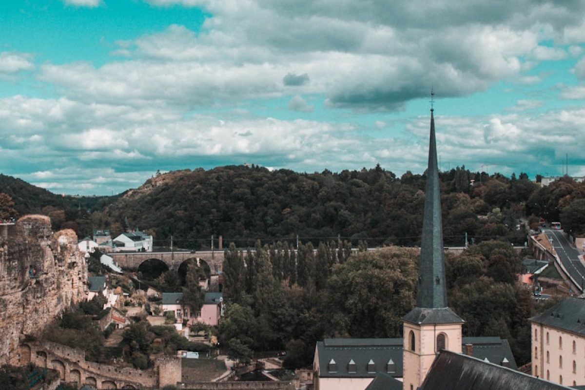 white and gray concrete building near green trees under white clouds and blue sky during daytime